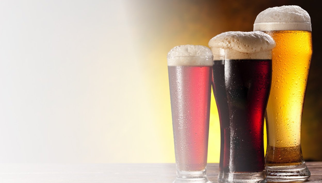 Foamy glasses of beer of various sizes and varieties