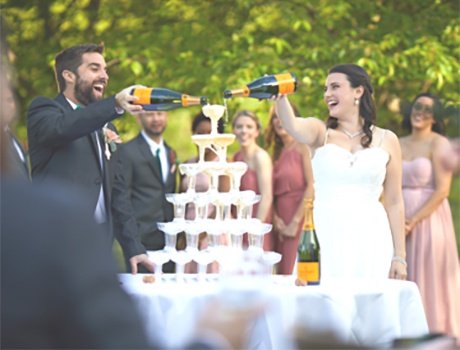Groom and bride pouring champagne on a pyramid of glasses