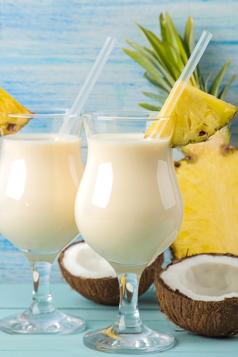 Piña Colada cocktails with fresh coconut halves and pineapple