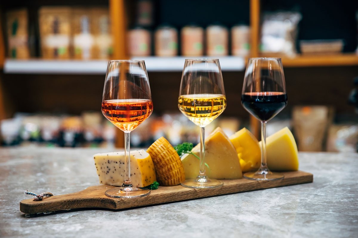 Glasses of rosé, white, and red wine with a cheese board