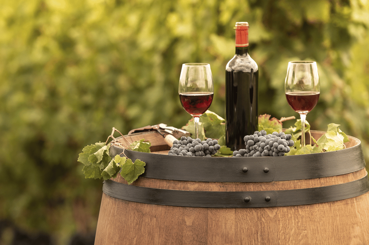 glasses of red wine and grapes on a barrel