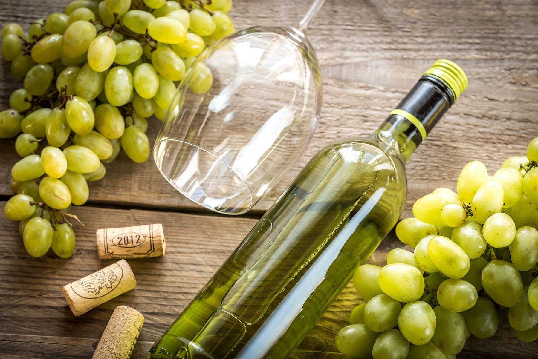 table of muscat grapes, wine glass, corks, bottle