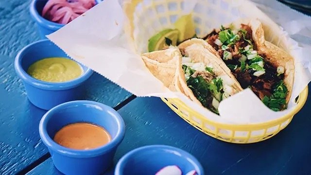 Tacos, sauce, vegetables, lime, blue table